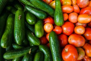 A vibrant display of juicy cucumbers and ripe tomatoes at a local market.