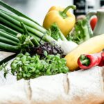 A vibrant assortment of fresh vegetables, herbs, and bread on a rustic surface, ideal for culinary scenes.